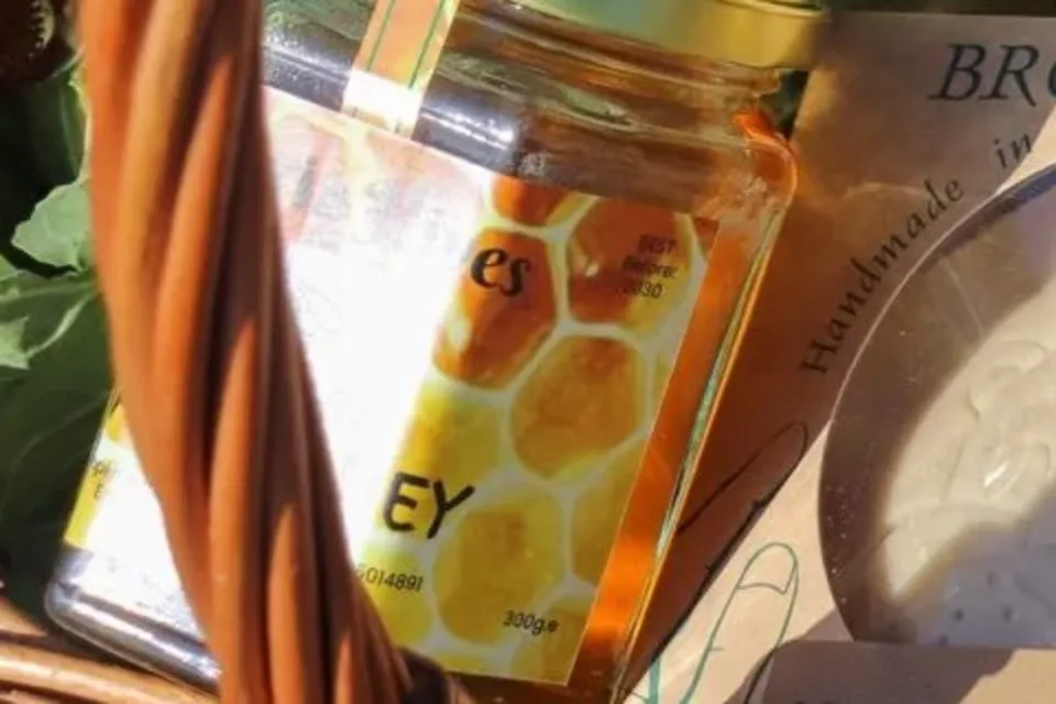 A jar of local honey with a honeycomb label in a market basket